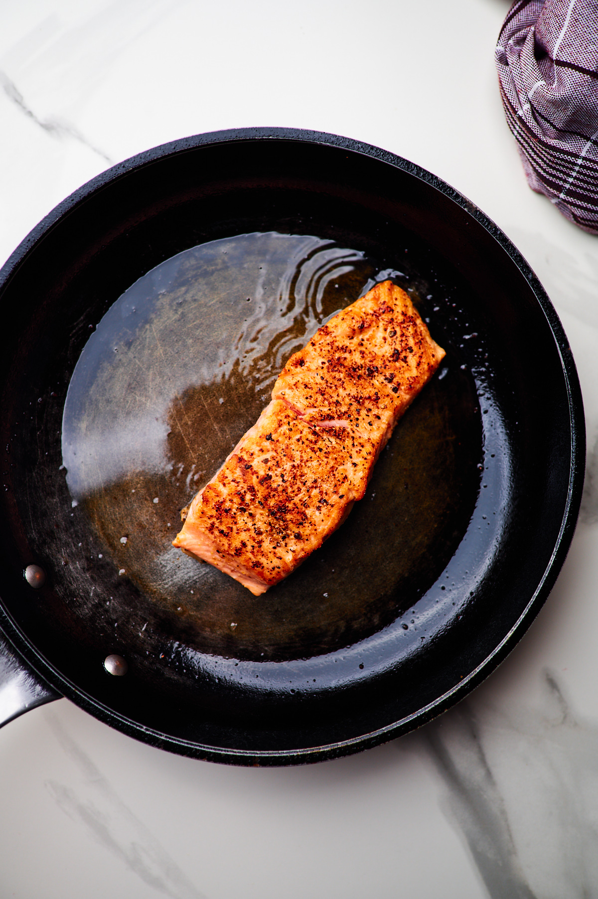 pan searing salmon fillet in a cast iron skillet and making the sauce for creamy salmon pasta in a skillet