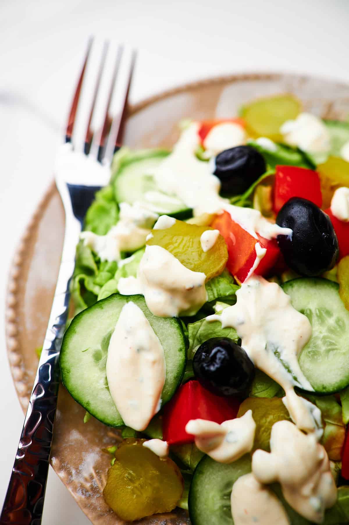 a bowl of salad with ranch dressing and a fork