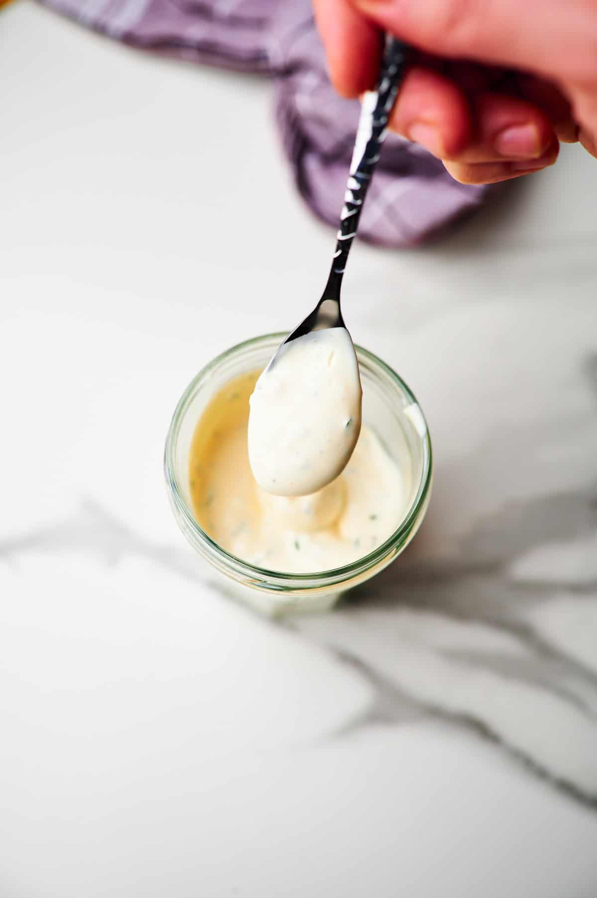 glass jar with homemade ranch dressing and a spoon with dressing on it