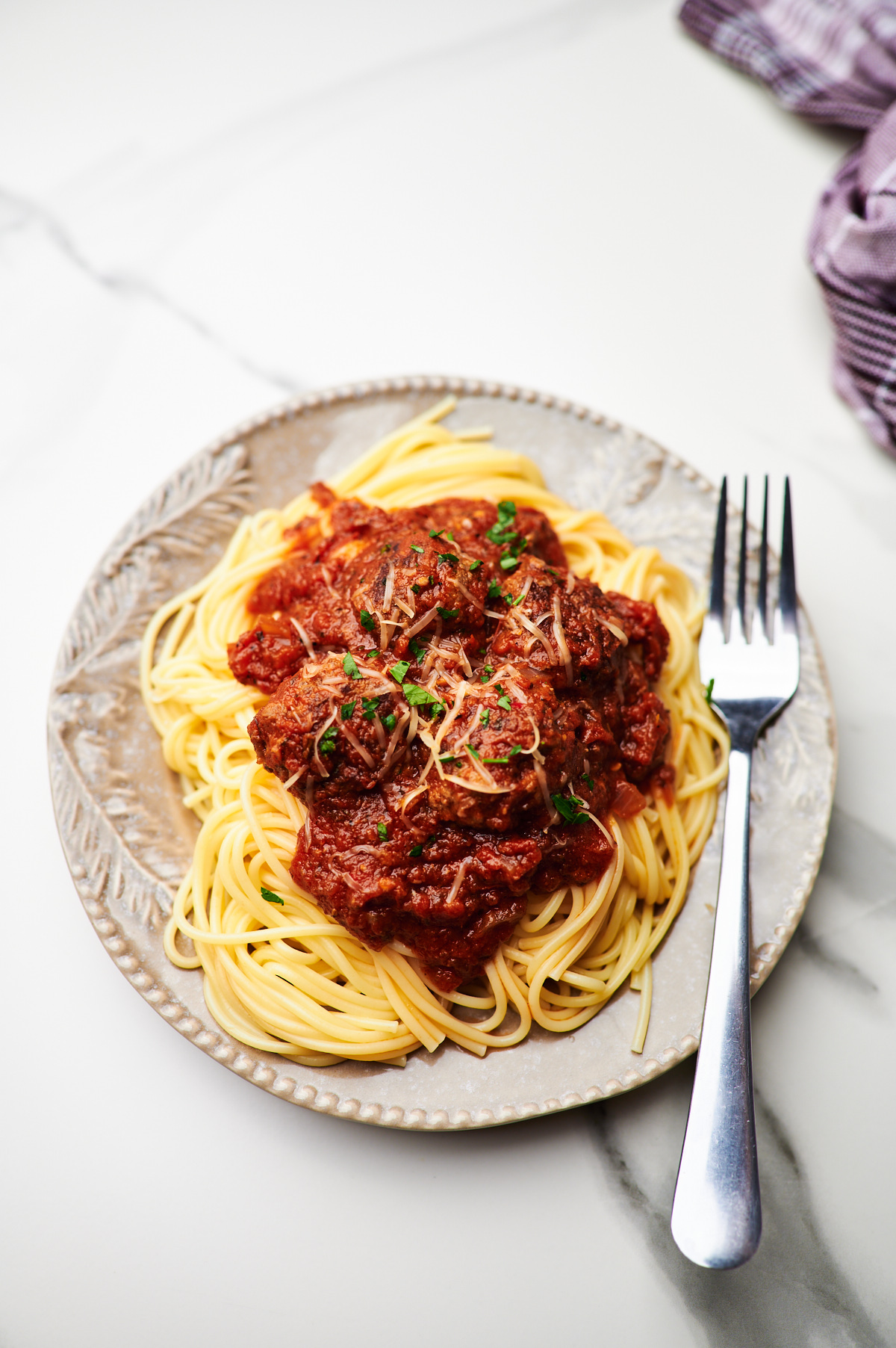 Overhead photo of Italian Meatballs in a rustic black bowl garnished with parmesan, ready to be eaten