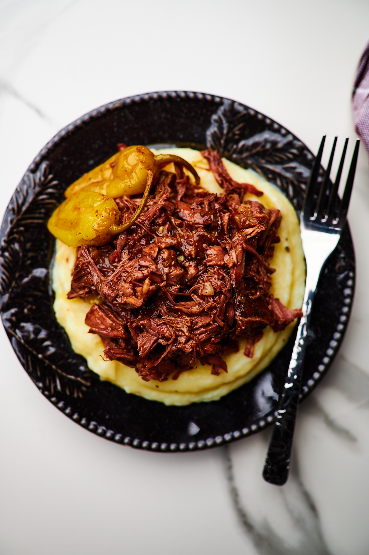 A plate of Mississippi pot roast on top of mashed potatoes 