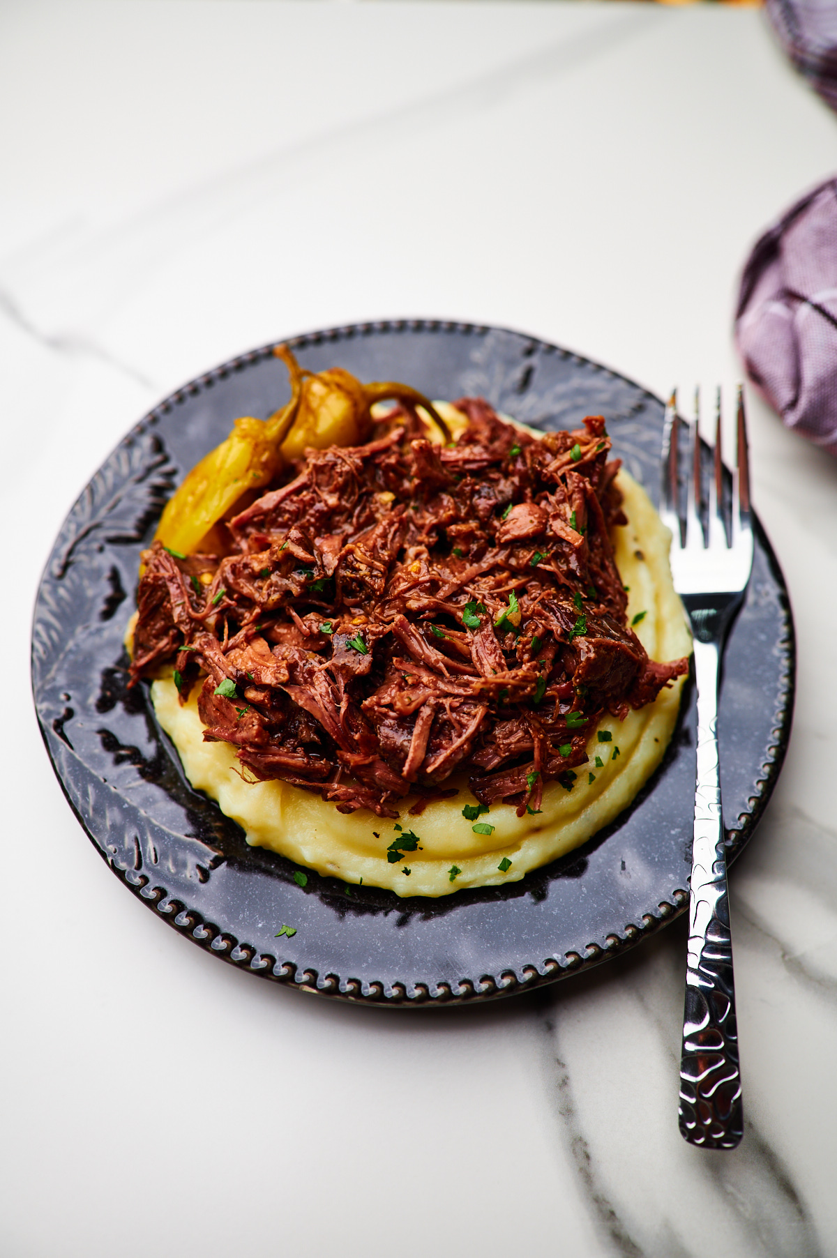 A plate of food Mississippi pot roast on top of mashed potatoes